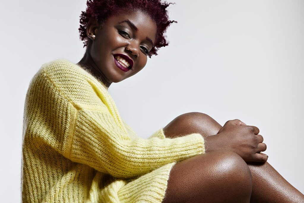 Viya health kenya shiny black woman wearing bright sweater touching her legs